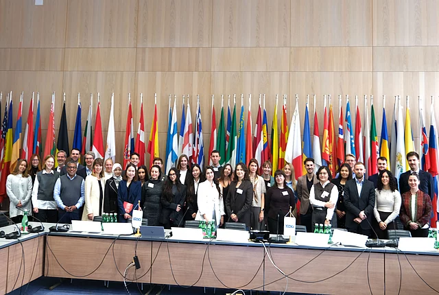 A photo shows the participants lined up before the background of flags at the OSCE Youth event